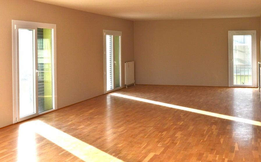 Salón vacío con suelo de parquet iluminado por el sol tras el vaciado del piso — Vaciado de pisos