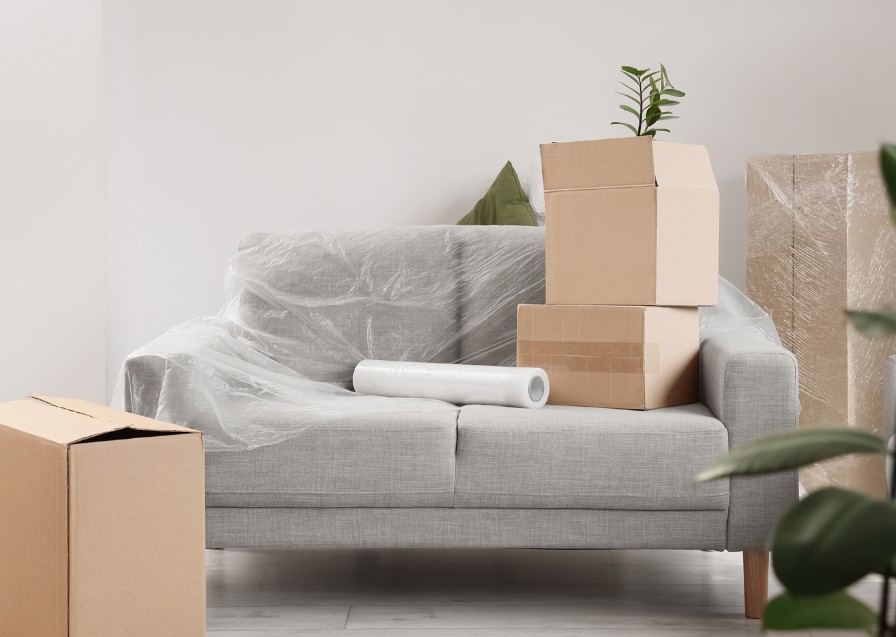 Sofá protegido con film y cajas de cartón preparadas para la recogida de muebles — Recogida de muebles